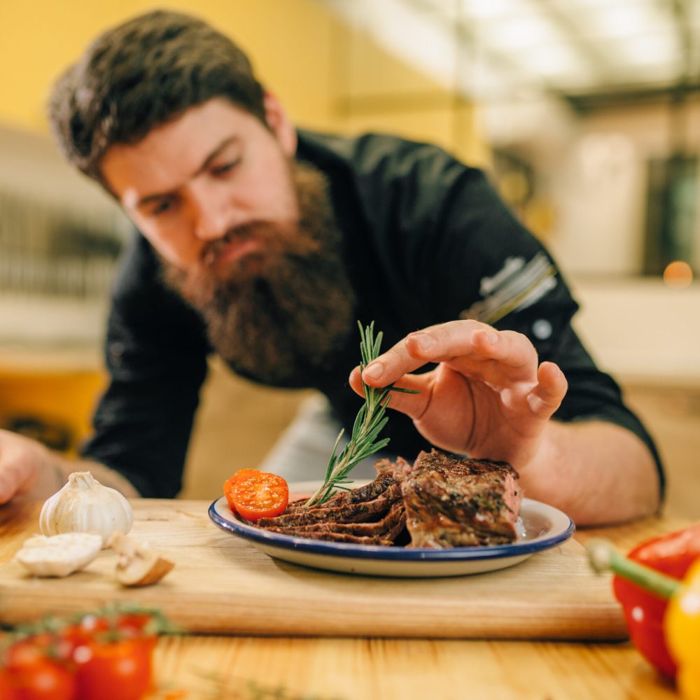 Chef decorates herbs roasted meat slices in plate